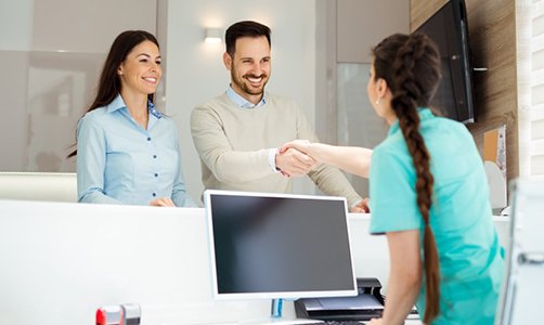 woman shaking hands with man over front desk 