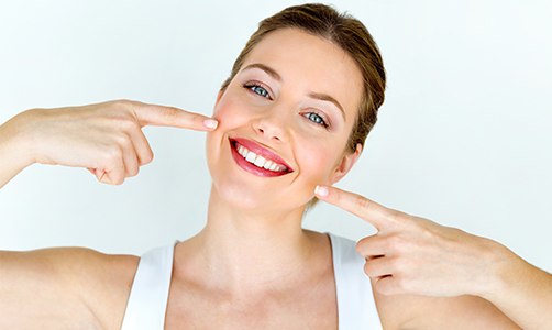 Woman pointing to teeth after smile makeover