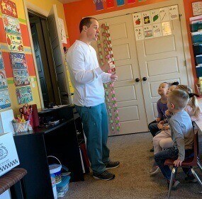Dentist teaching class of kids about oral health