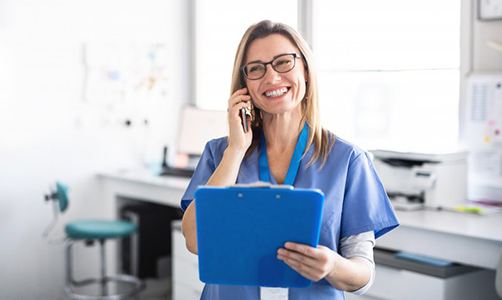 dental assistant talking on phone and holding blue clipboard 