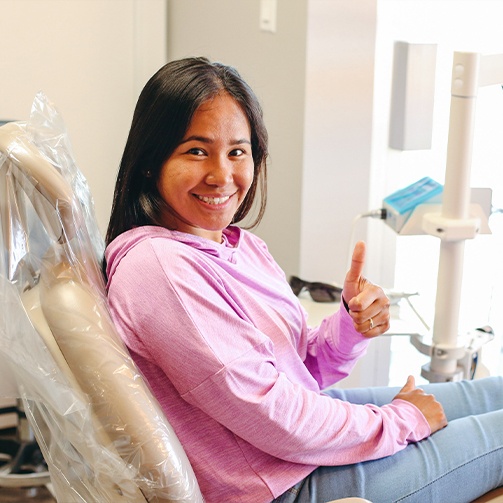 Woman at dental office for restorative dentistry giving thumbs up