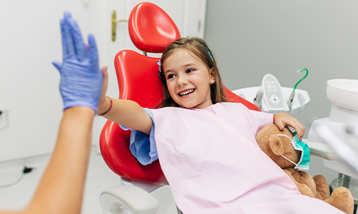 Little girl giving dentist a high five during dental checkup