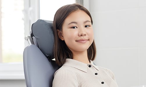 Smiling girl in dental chair after dental sealant application