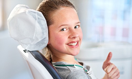 Young girl giving thumbs up after tooth-colored fillings placement