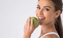 woman biting into a green apple
