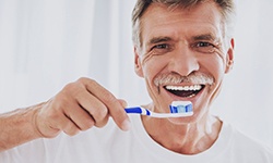 man brushing teeth after dental implant surgery in Idaho Falls