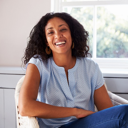 Woman in light blue shirt smiling in chair at home