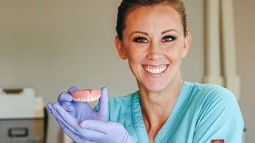 Smiling dental team member holding a denture