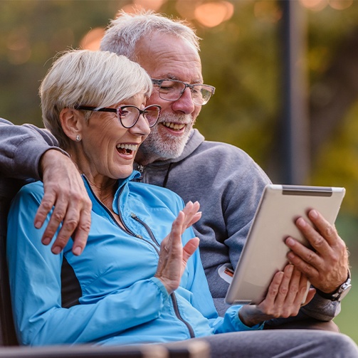Smiling older couple holding virtual smile consultation on tablet