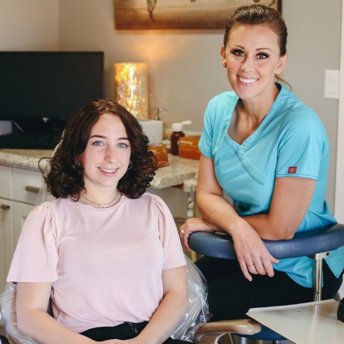 Dental team member and patient smiling after teeth whitening